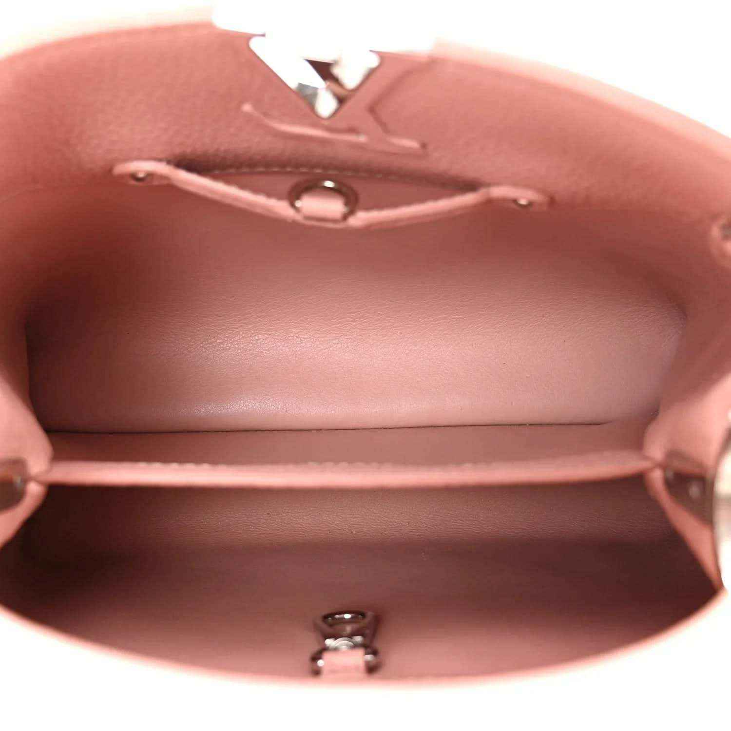 Open pink handbag interior with stitched top edge and small metal zipper pull