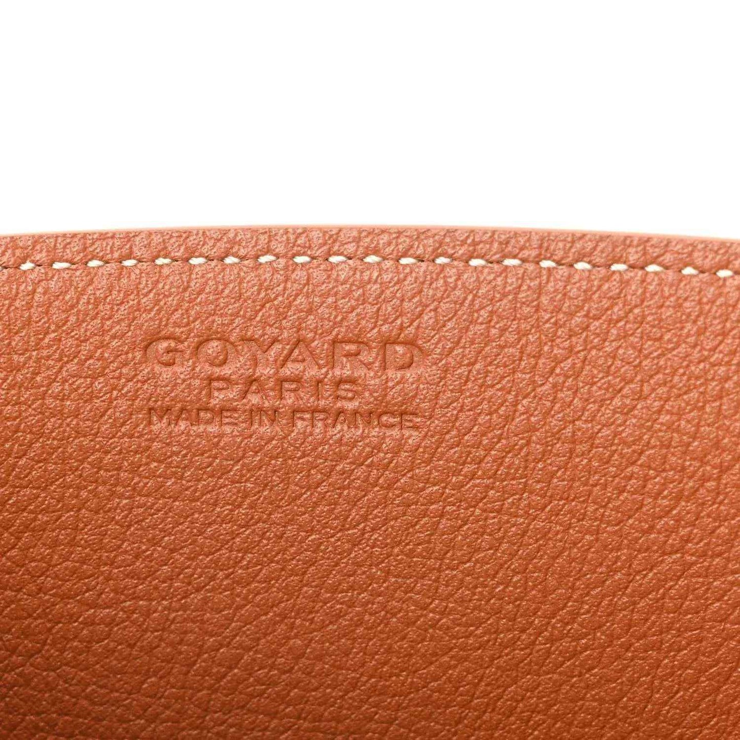 Tan leather mini tote bag panel with embossed brand lettering and stitching along the edge.