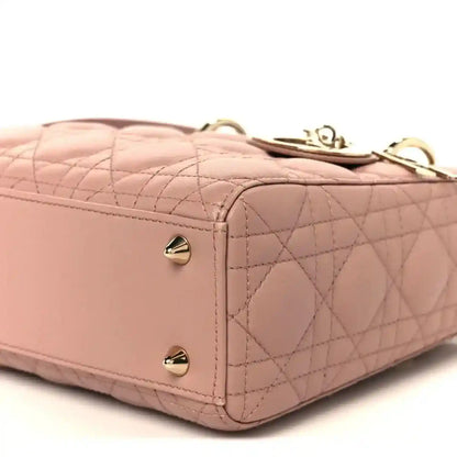 Top corner of blush pink quilted bag with gold-tone studs and leather trim