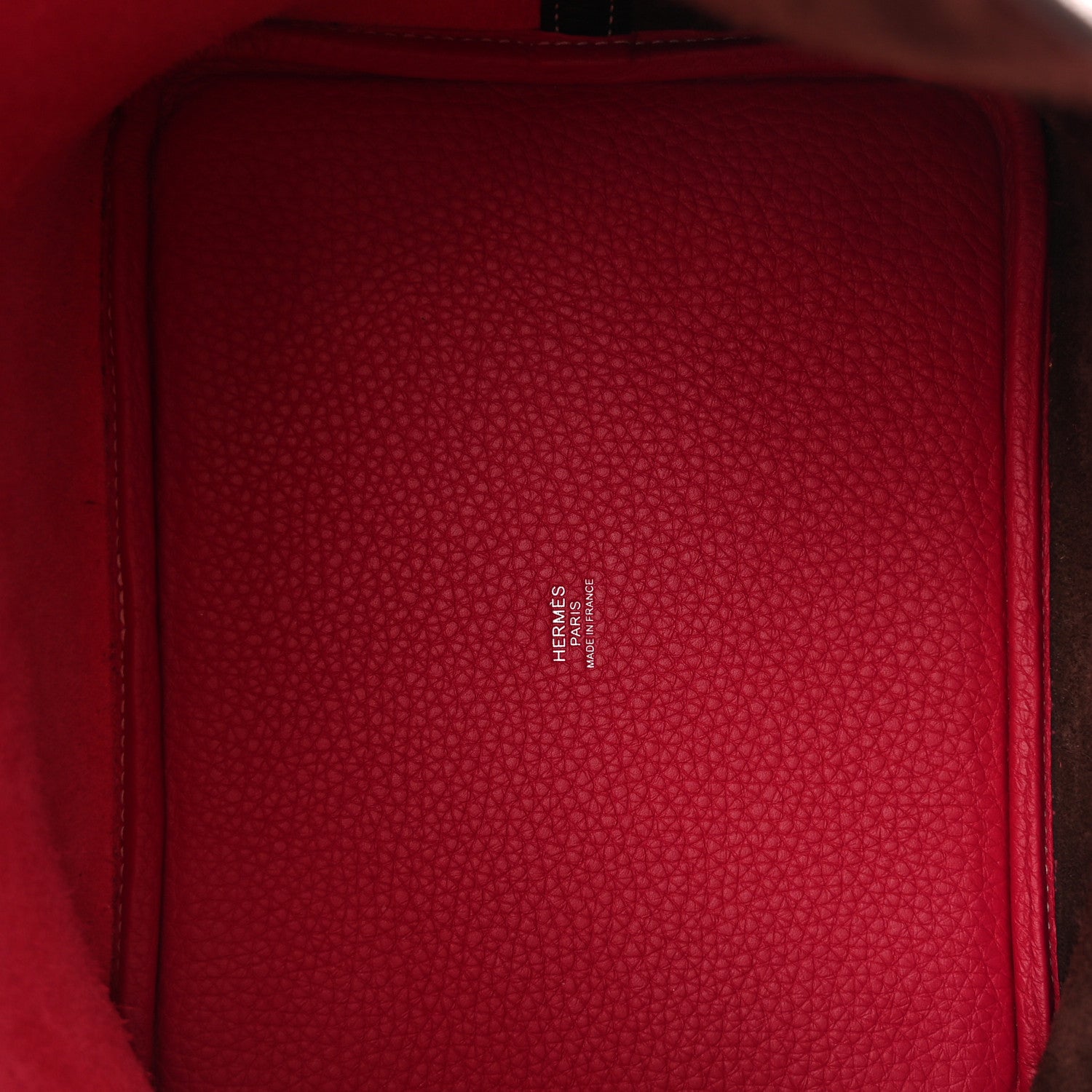 Red leather-lined interior of bucket bag with embossed logo text