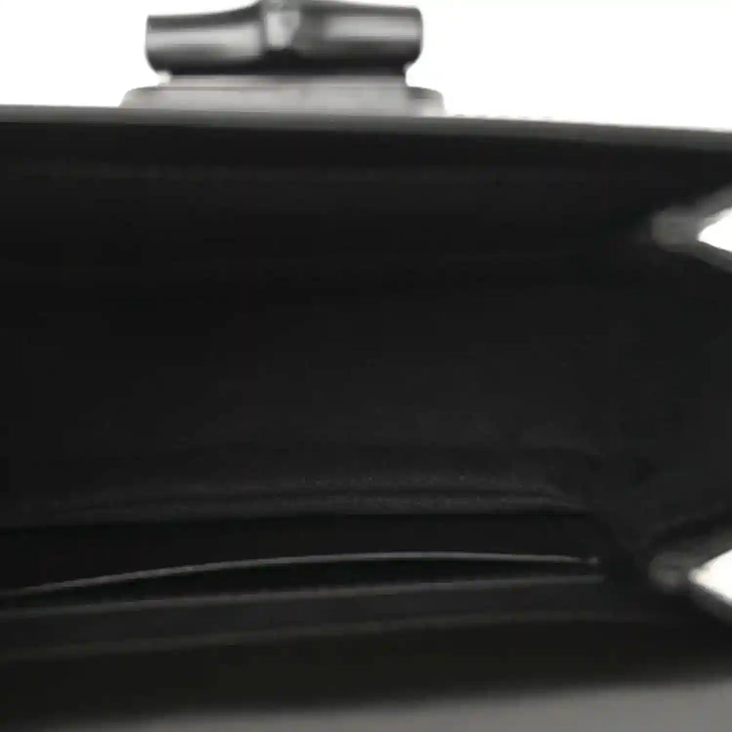 Black handbag close-up of a seam and metallic hardware detail near top.