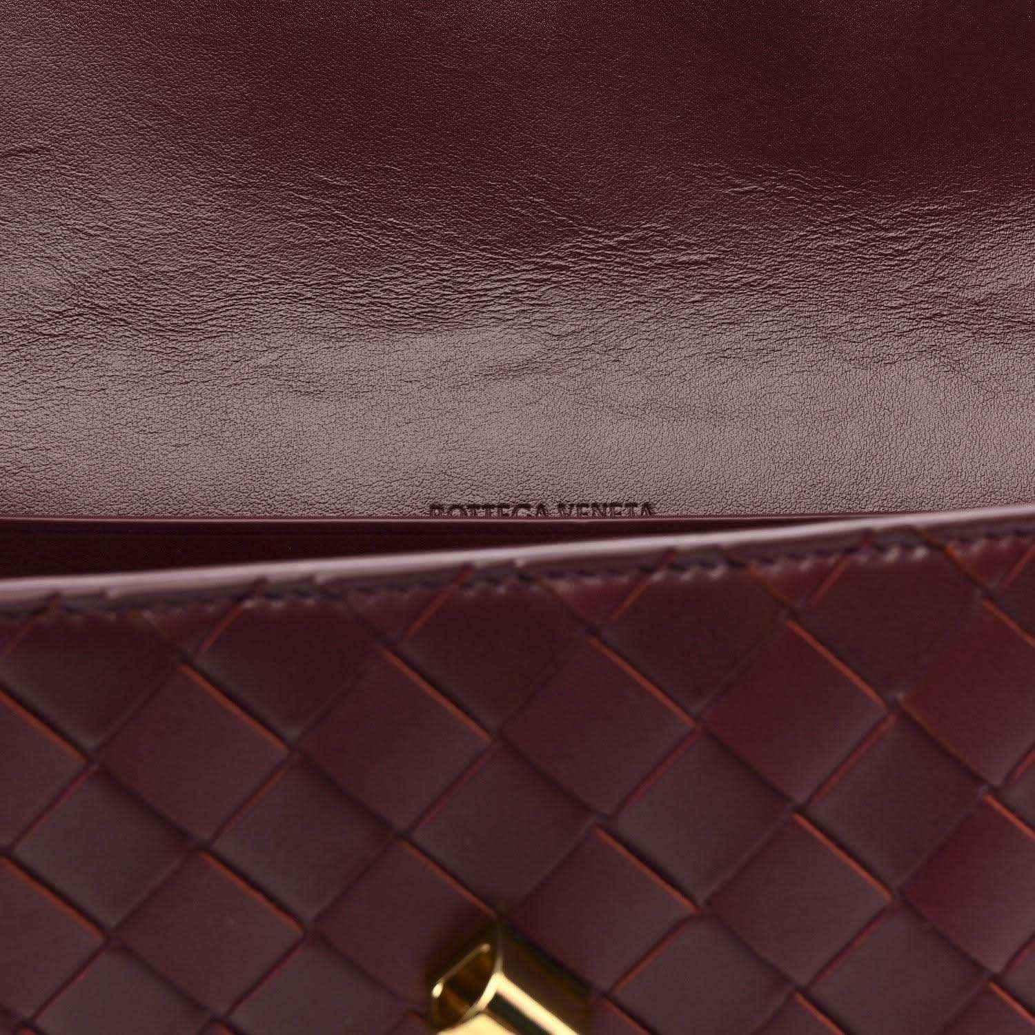 Burgundy intrecciato clutch close-up with embossed logo and gold hardware corner