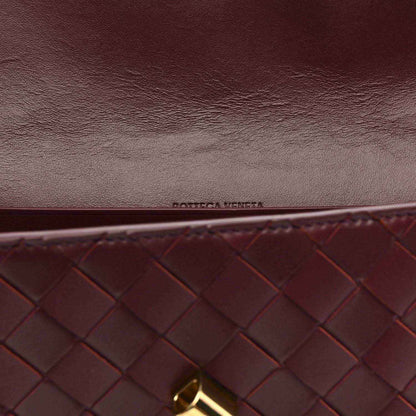 Burgundy intrecciato clutch close-up with embossed logo and gold hardware corner