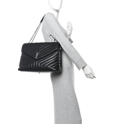 Black quilted leather chain satchel with YSL logo, held over the shoulder