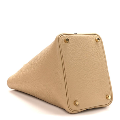 Beige leather tote bag with corner studs and structured triangular side profile
