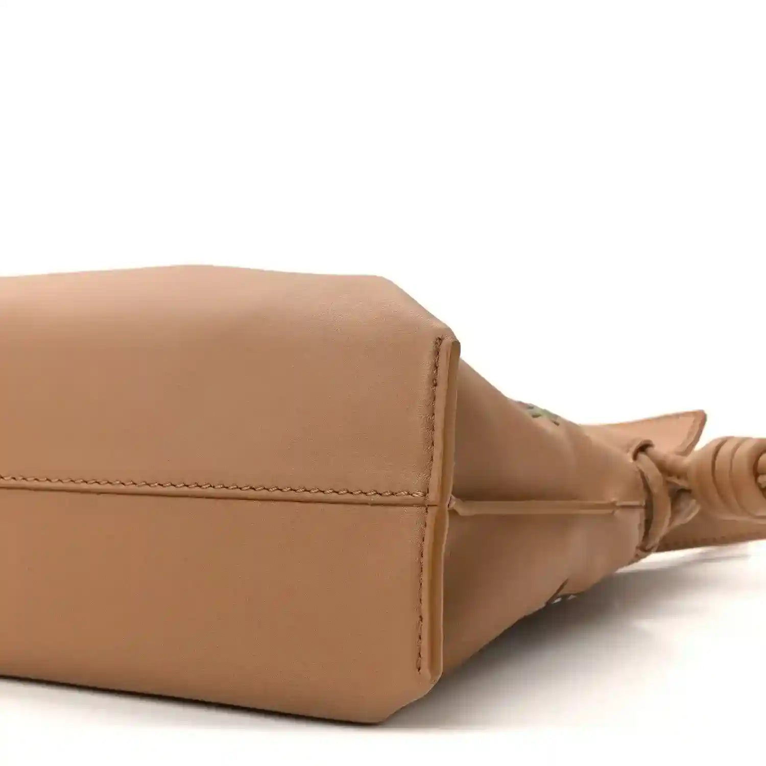 Tan leather mini clutch corner with edge stitching and knotted strap end.
