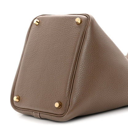 Taupe leather bucket bag with gold corner studs and curved base.