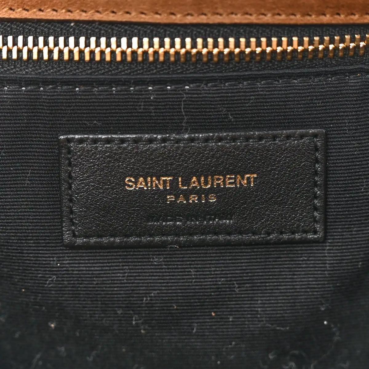 Saint Laurent interior fabric label on dark lining with gold zipper hardware.