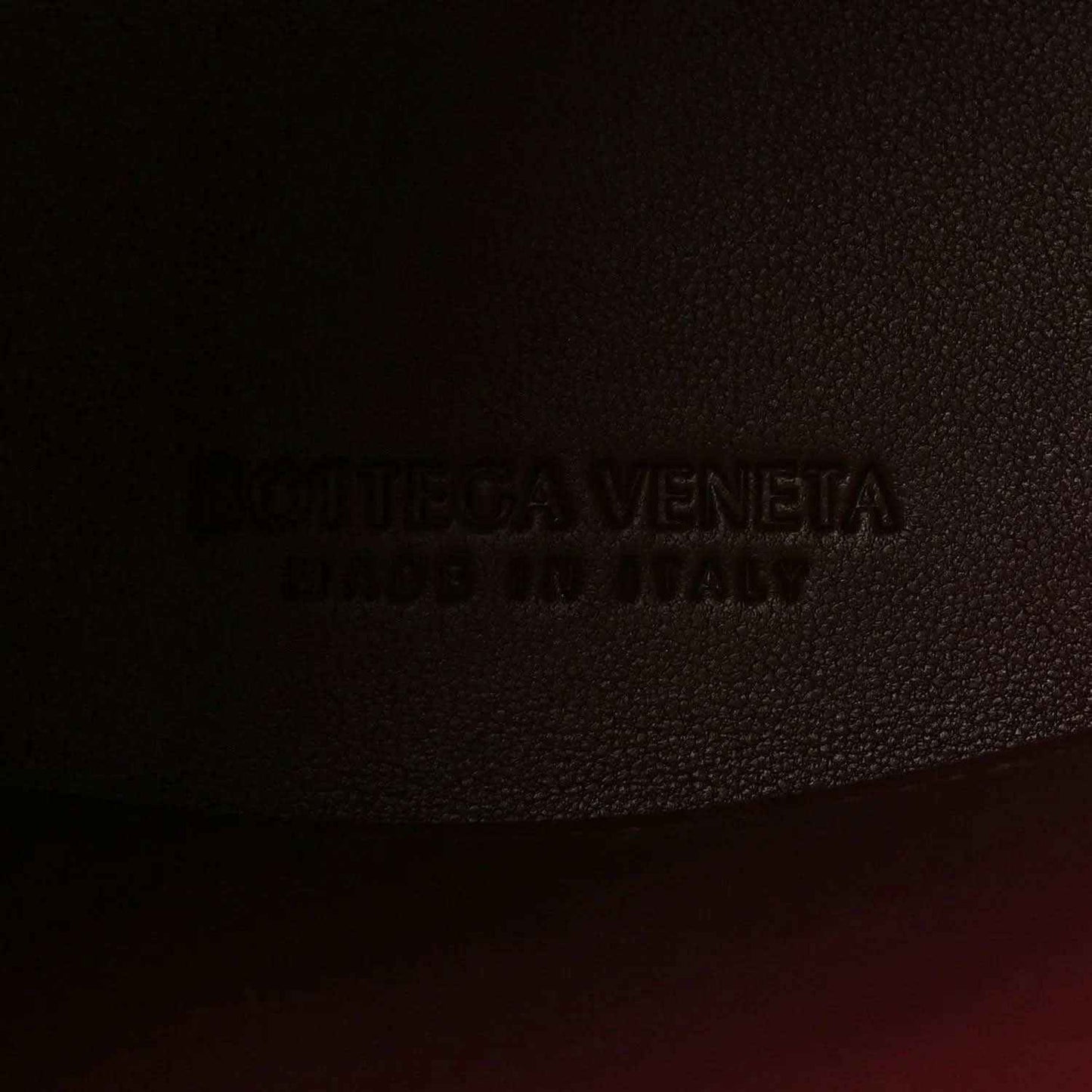 Bottega Veneta logo stamp on burgundy textured leather lining.