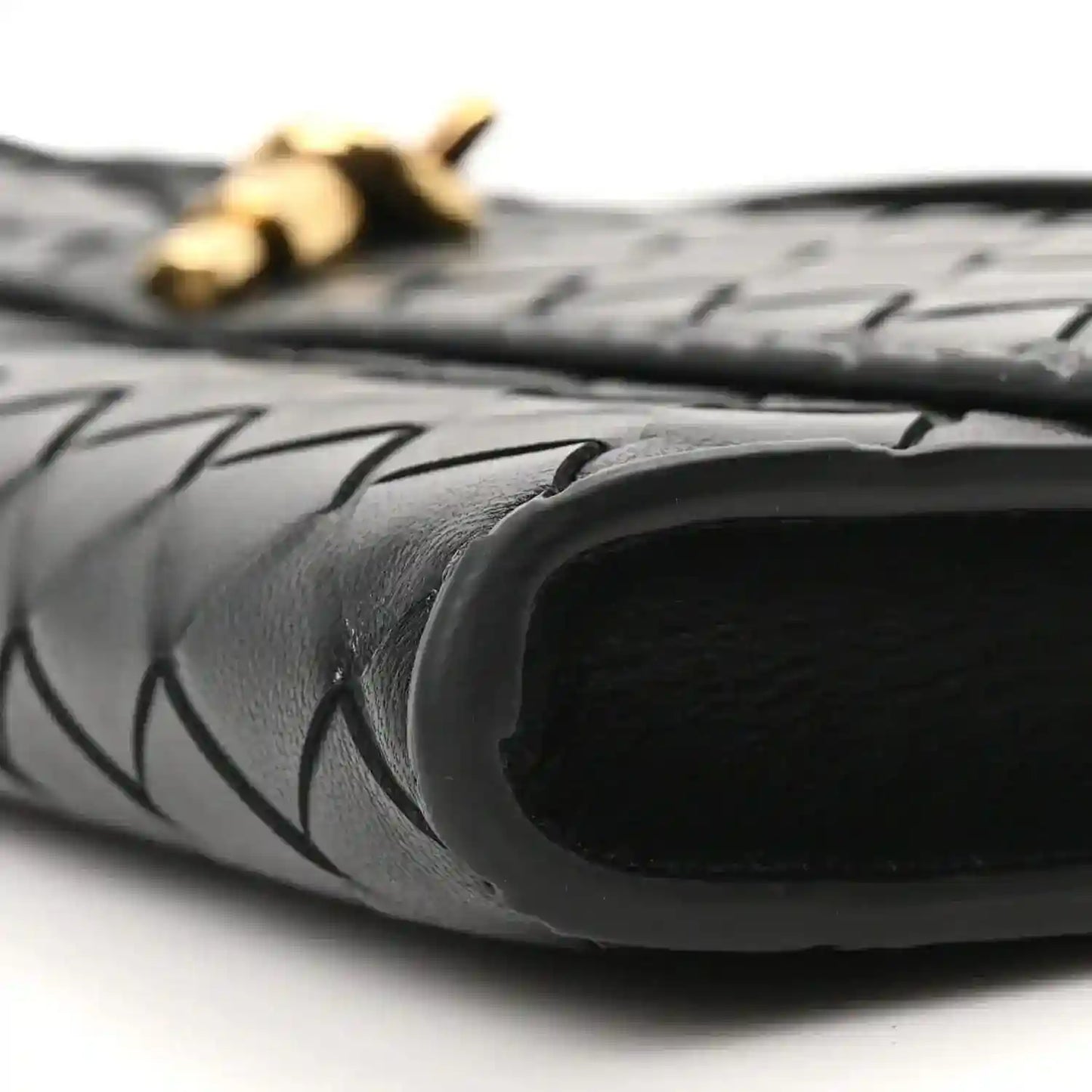 Black clutch interior opening with woven leather edge and gold hardware