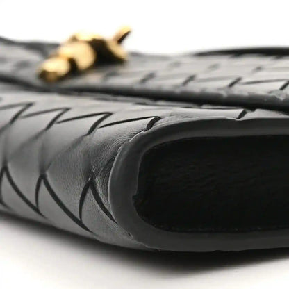 Black clutch interior opening with woven leather edge and gold hardware