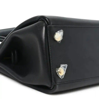 Black leather handbag corner with gold-tone stud detail