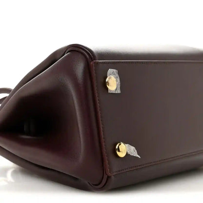 Loewe Small Madrid bag side close-up in dark burgundy calfskin with gold snap hardware