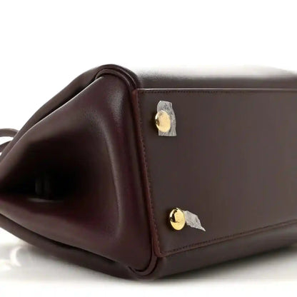 Loewe Small Madrid bag side close-up in dark burgundy calfskin with gold snap hardware