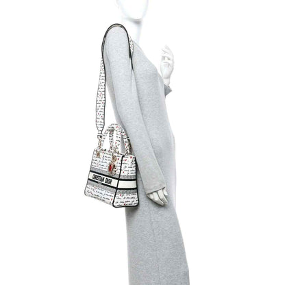 Christian Dior canvas handbag worn crossbody, “Je vous adore” print, gold hardware