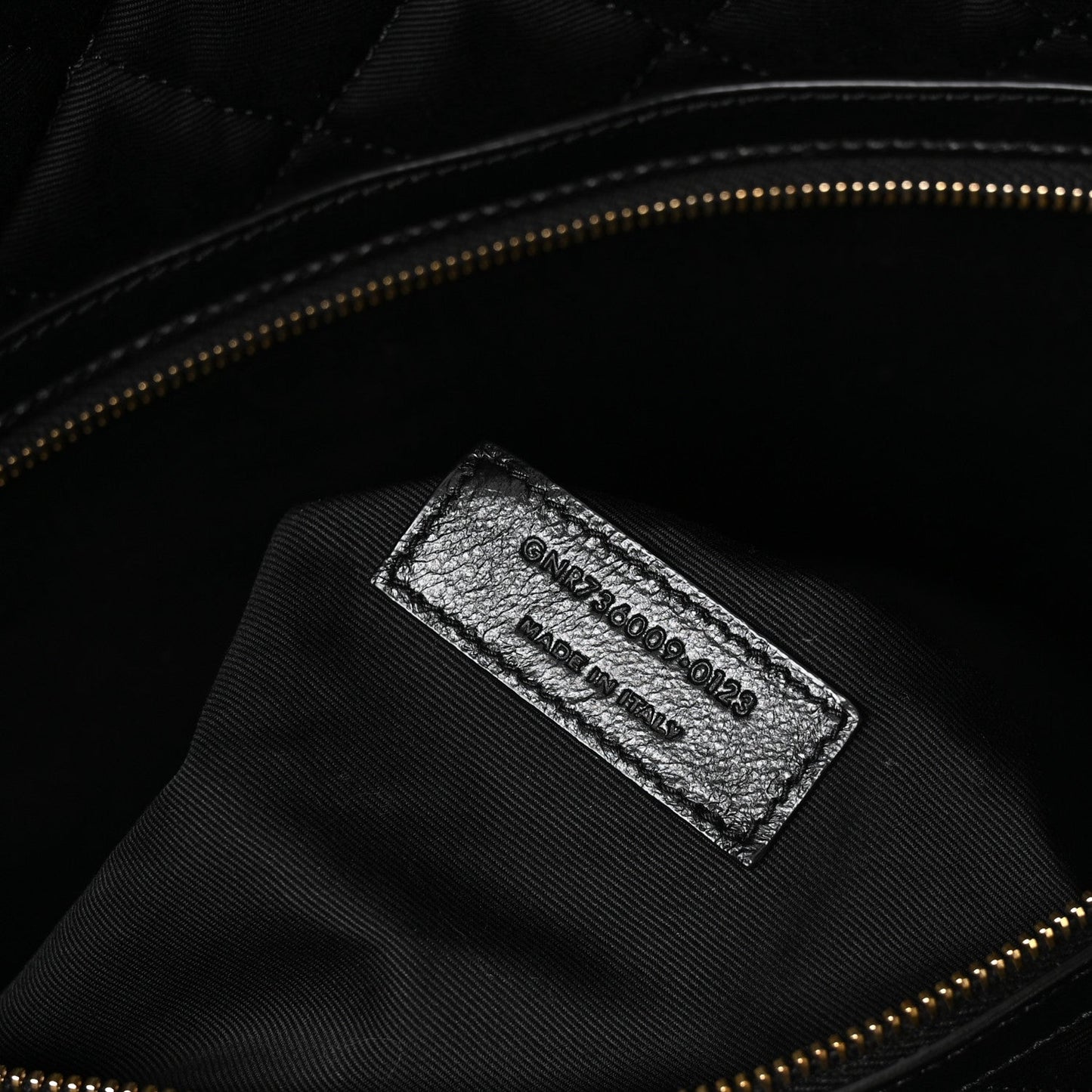 Black leather interior brand label with stamped text and gold zipper trim