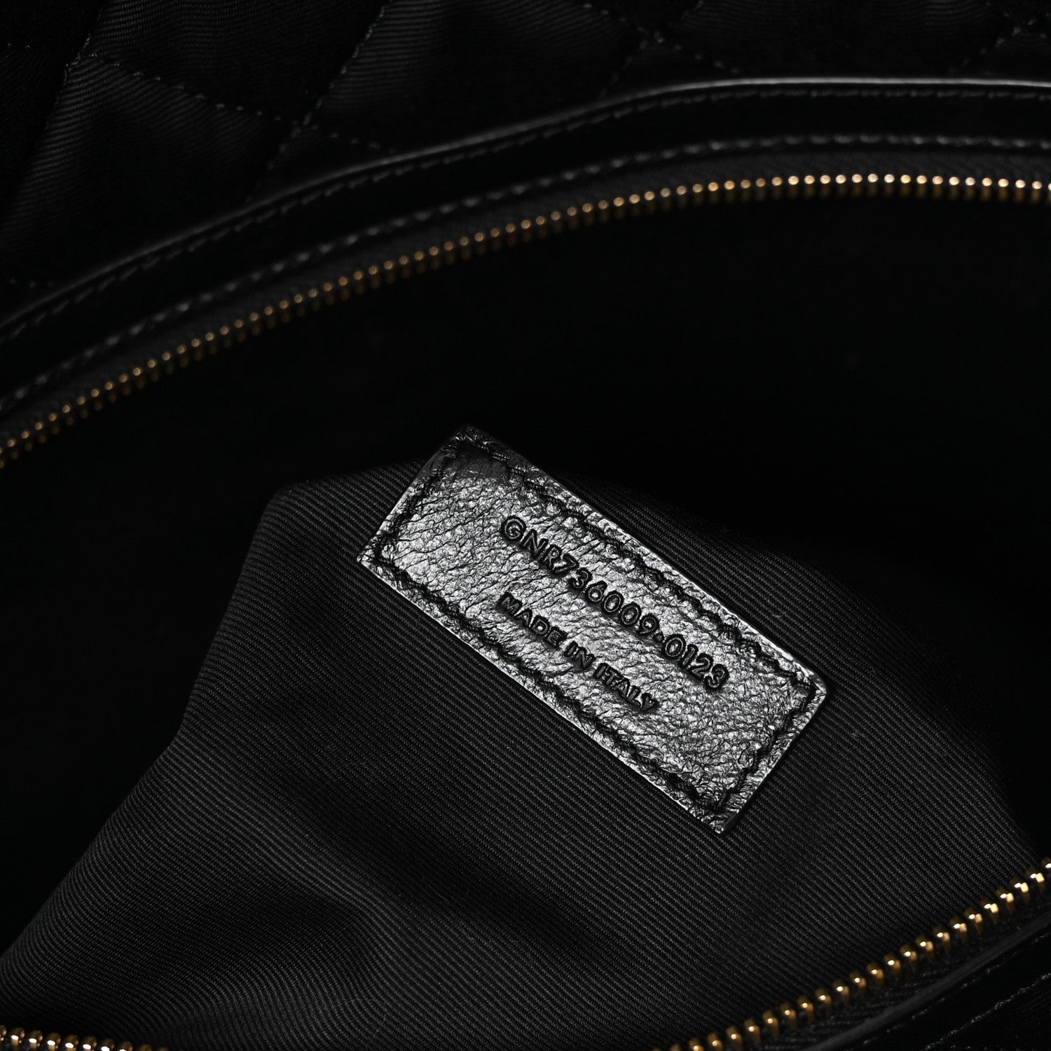 Black leather interior brand label with stamped text and gold zipper trim