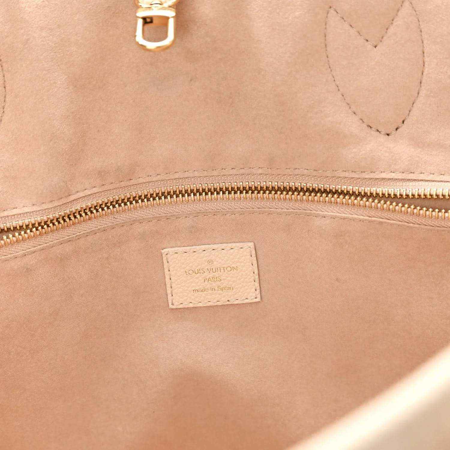 Louis Vuitton Neverfull MM tote bag interior close-up with brand patch and gold zipper