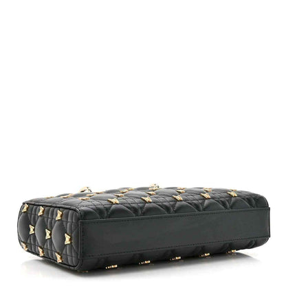 Black quilted handbag with butterfly embellishments and gold accents, side/bottom view