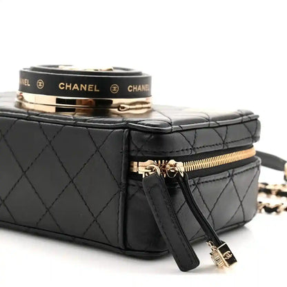 Black quilted lambskin mini bag top with clasp band, zipper pull, and wrist strap