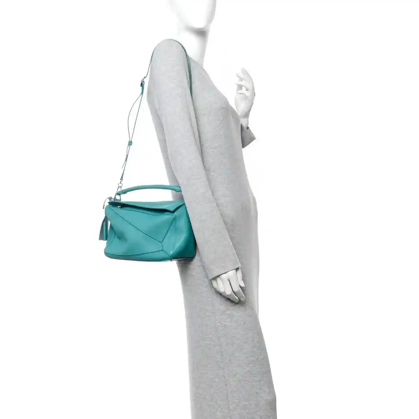 Teal-blue small Puzzle bag carried with long crossbody strap; front view on model.