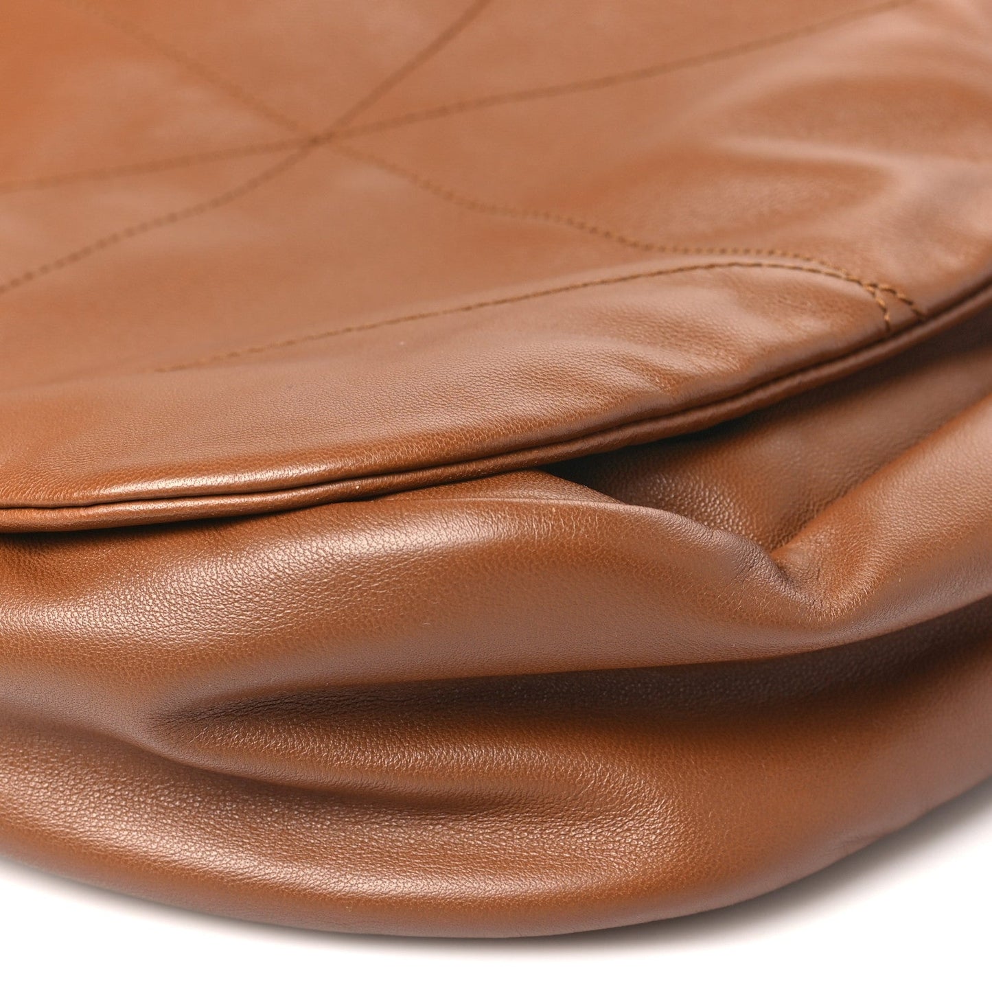 Close-up of tan quilted leather seam and smooth fold at bag opening