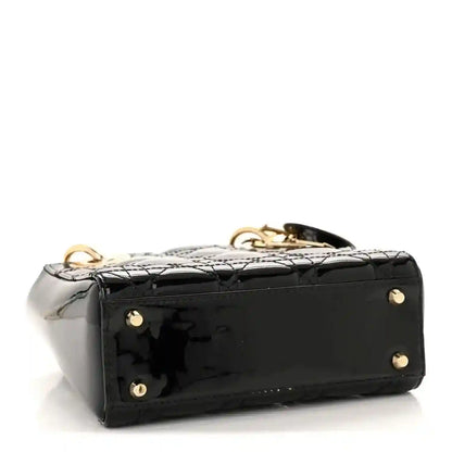 Black patent mini handbag side view with gold feet studs and top handle hardware