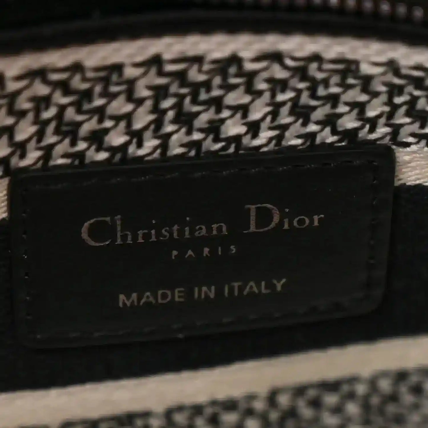 Black leather logo patch reading 'Christian Dior Paris Made in Italy' on houndstooth bag