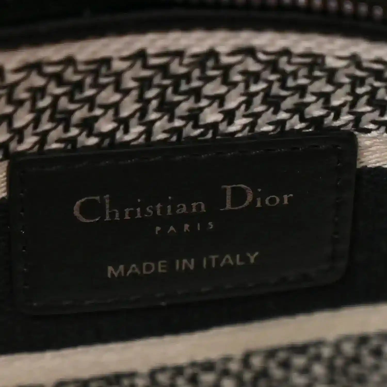 Black leather logo patch reading 'Christian Dior Paris Made in Italy' on houndstooth bag