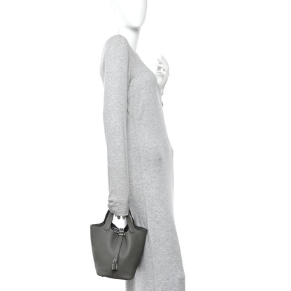 Leather bucket bag on a model’s shoulder, dark green with short top handles