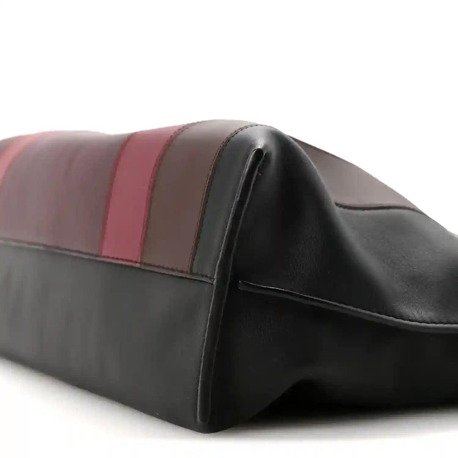 Clutch bag corner close-up showing black edge piping and striped leather bands