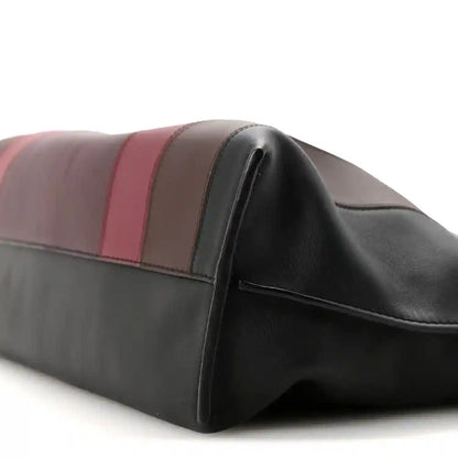 Clutch bag corner close-up showing black edge piping and striped leather bands
