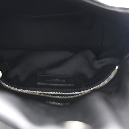 Black satin-lined interior of small satchel with zipper opening and silver chain detail.