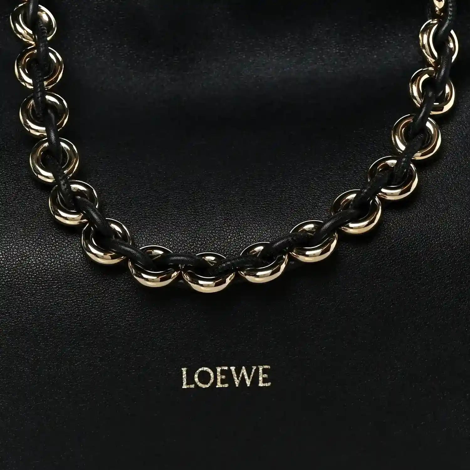 Black leather clutch with chunky gold-tone chain strap and centered LOEWE logo.