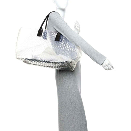 Large tote bag with white woven PVC and black leather handles, worn on arm