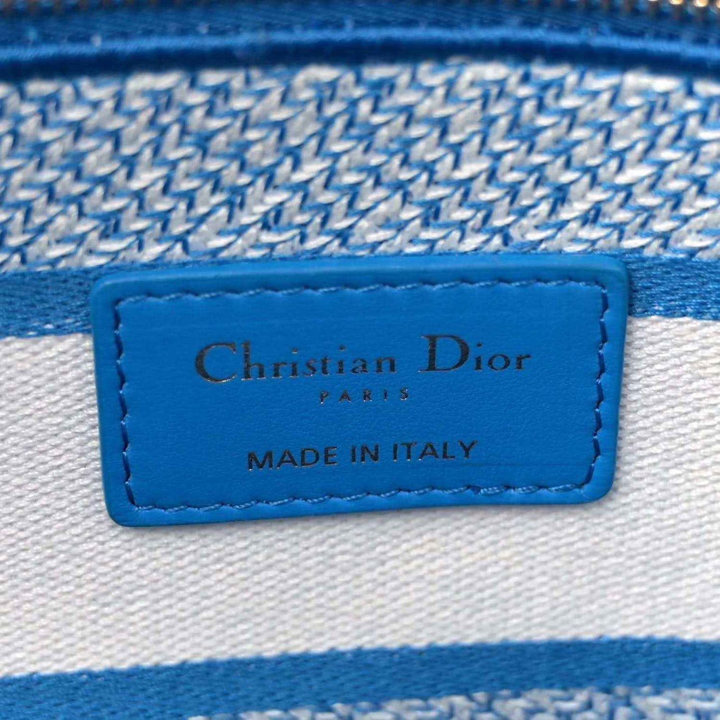 Blue-and-white embroidered bag interior label reading Christian Dior Paris, made in Italy.