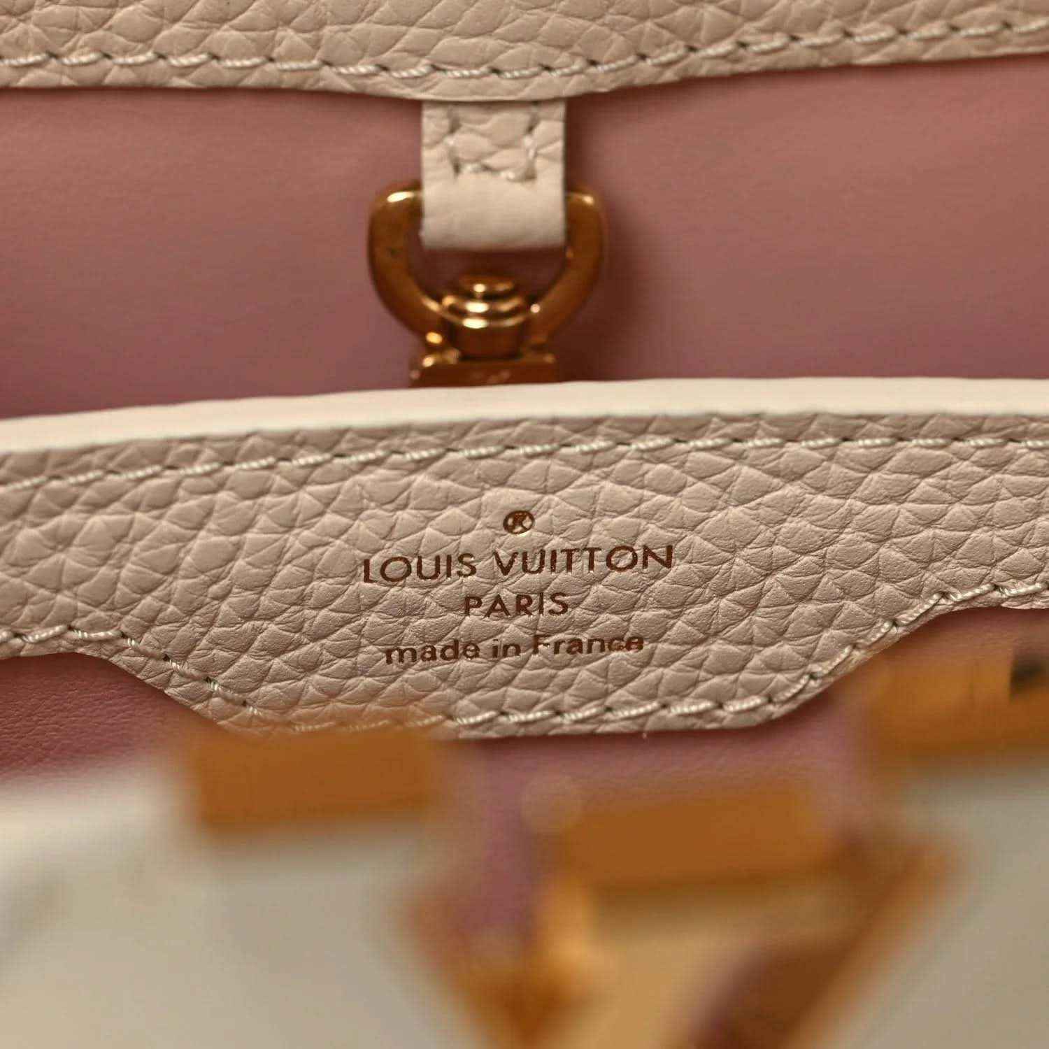 Louis Vuitton Paris label on beige leather handbag with gold clasp detail