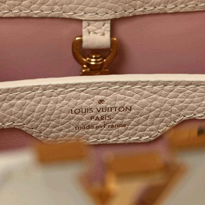 Louis Vuitton Paris label on beige leather handbag with gold clasp detail