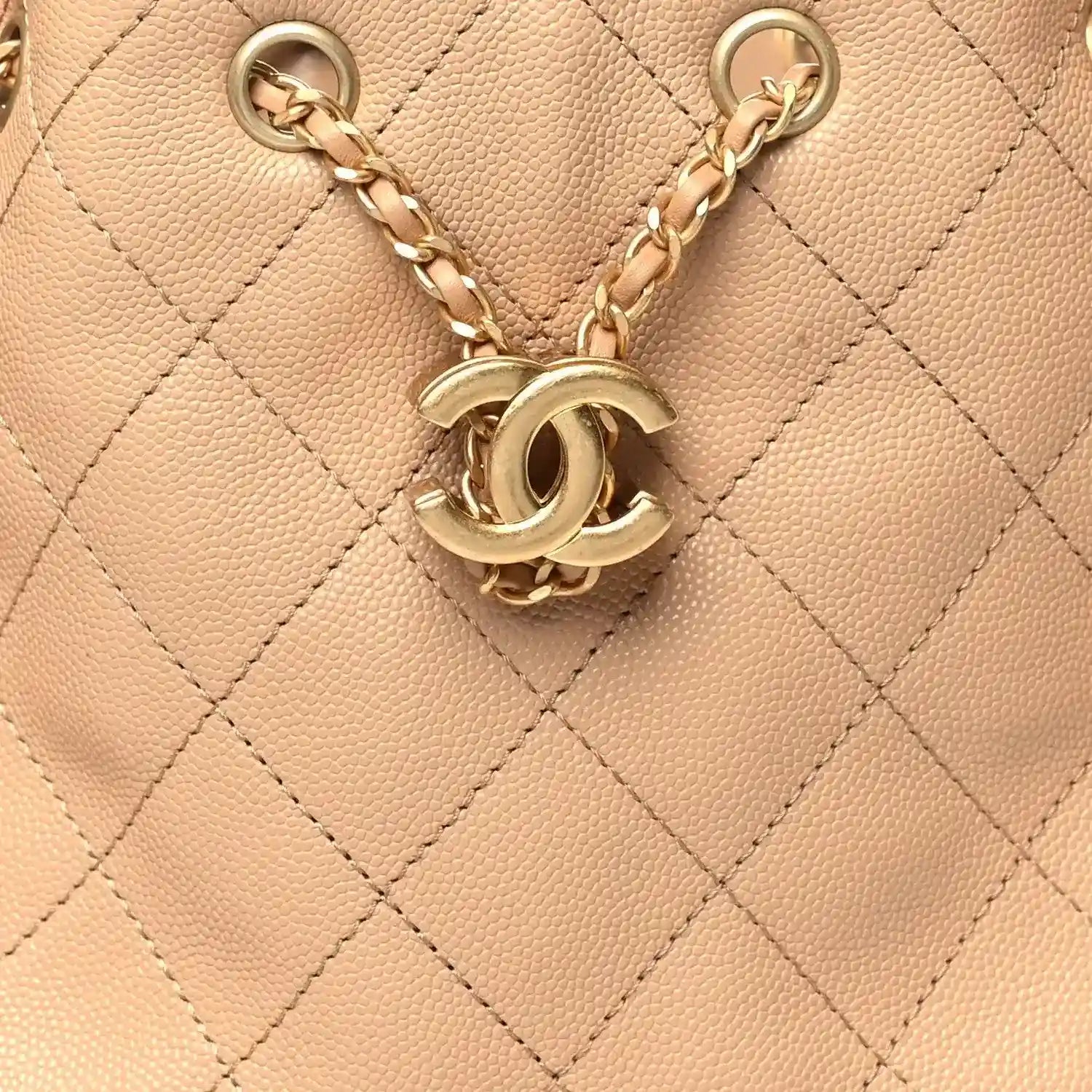 Chanel quilted handbag charm with CC logo and gold tone chain hardware on beige leather