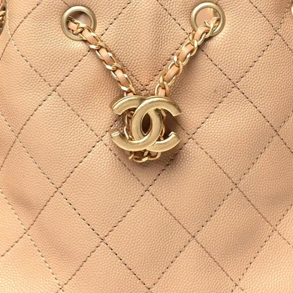 Chanel quilted handbag charm with CC logo and gold tone chain hardware on beige leather