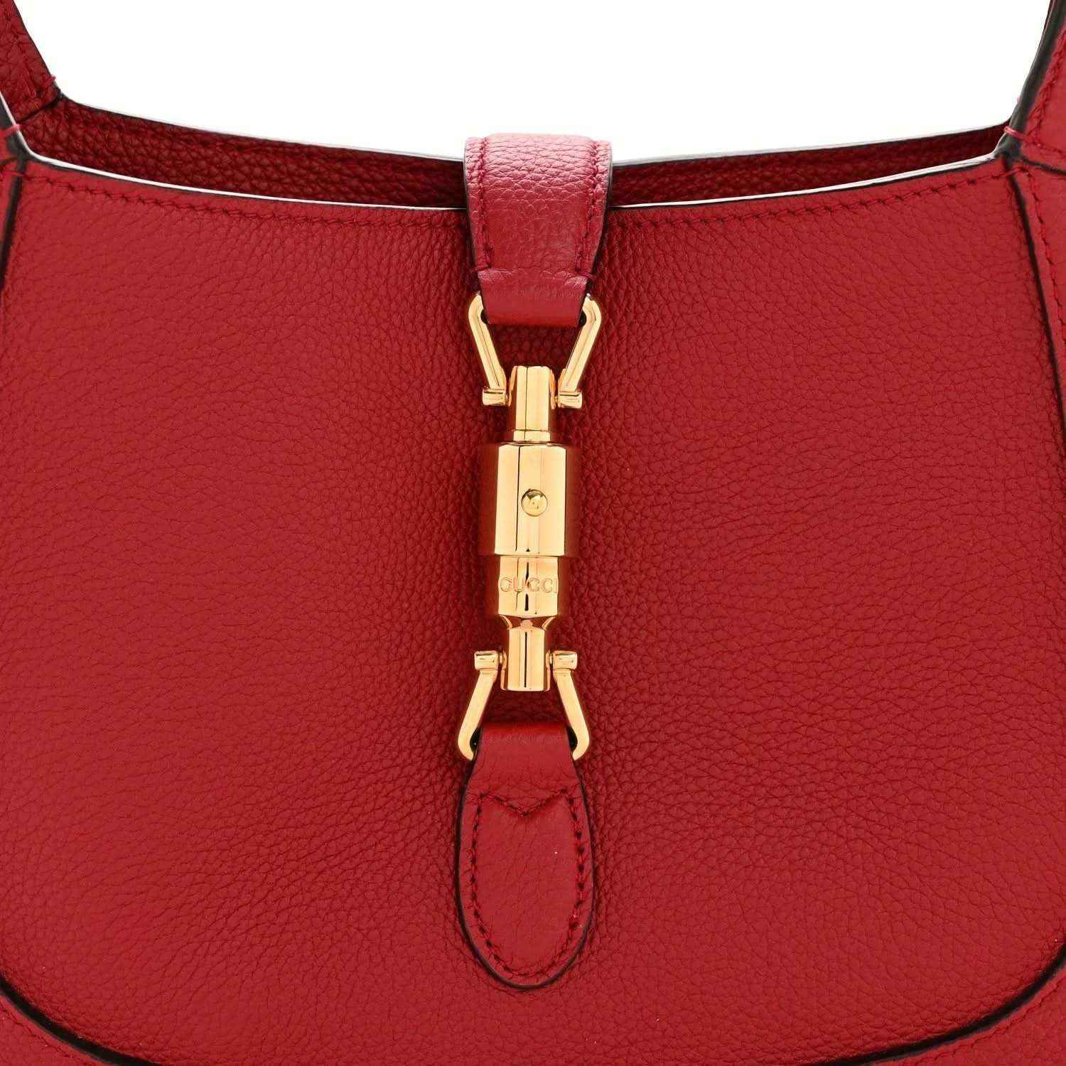 Red leather hobo bag close-up of gold clasp and leather tab at top