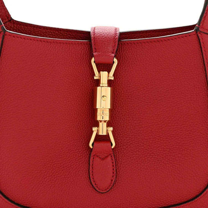 Red leather hobo bag close-up of gold clasp and leather tab at top