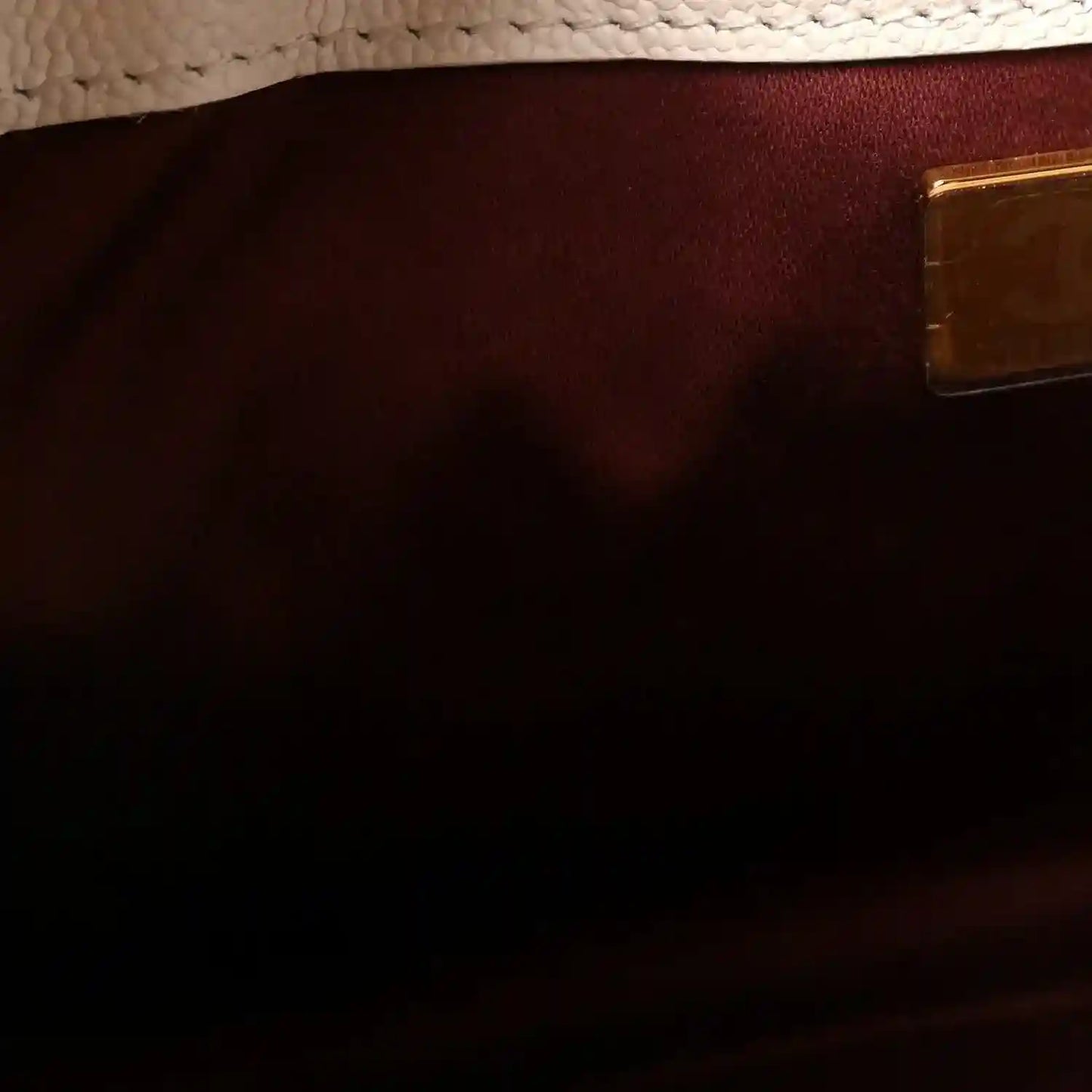 Mini handbag interior pocket with dark burgundy lining and small rectangular leather patch