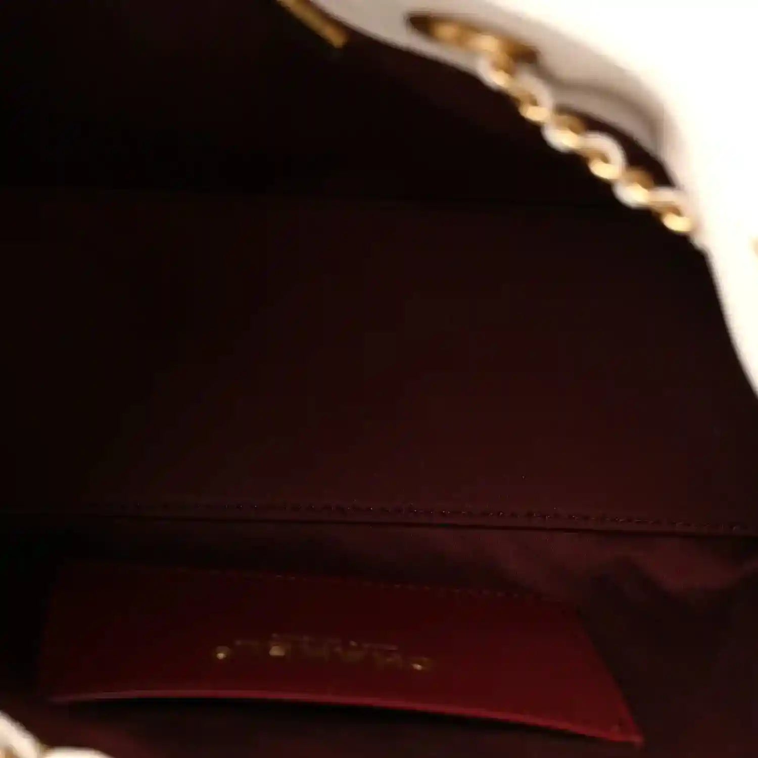 Mini handbag interior lining in dark burgundy with stitched panel and gold-tone hardware edge