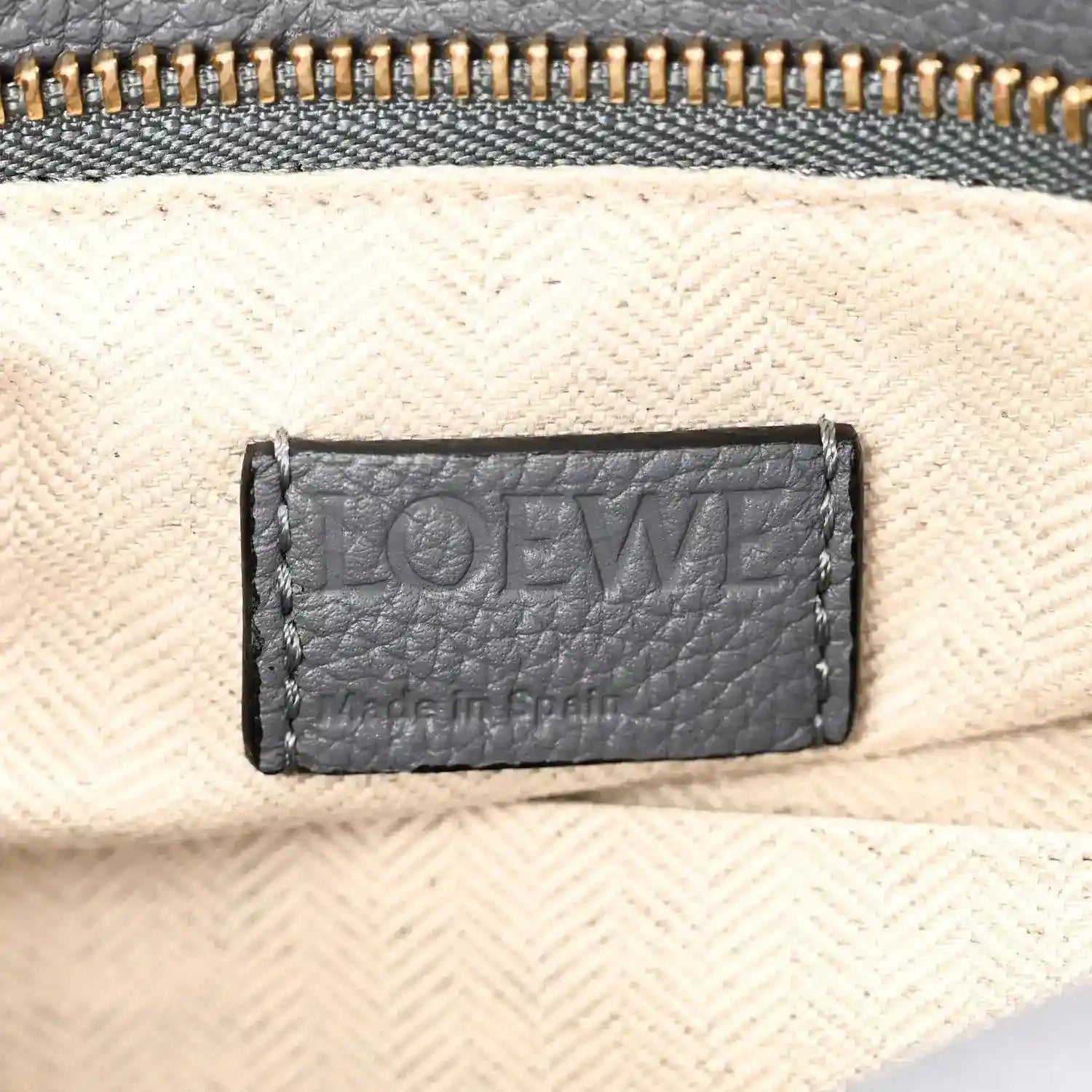 Small puzzle bag interior label on light lining with dark gray leather trim