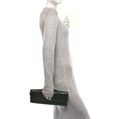 Black woven leather top-handle clutch shown in side carry position