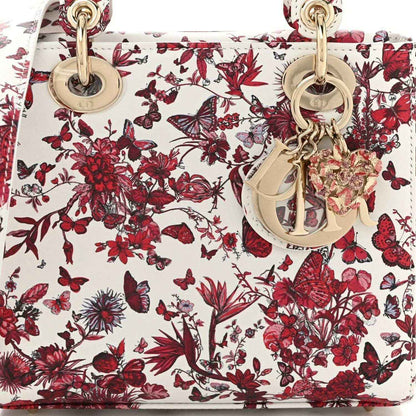 Close-up of small handbag exterior with red-and-white floral print and gold-tone key charm
