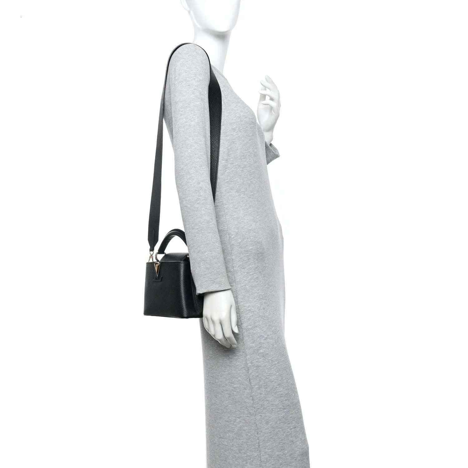 Black mini Capucines leather bag worn crossbody with adjustable strap and gold-tone LV detail