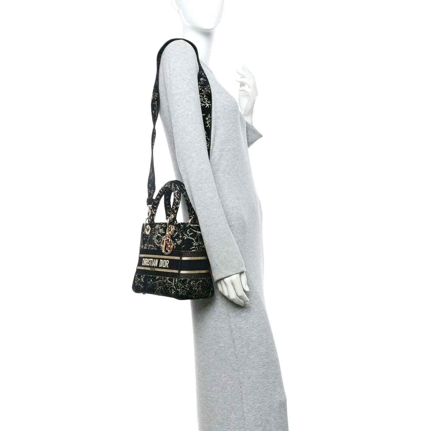 Black embroidered handbag with gold trim, worn by a model in side profile