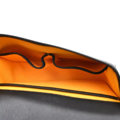 Orange-lined interior of a black messenger bag with visible zipper and seams